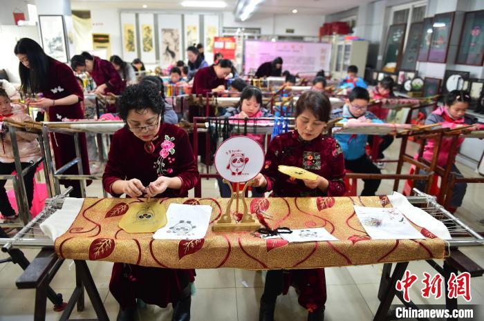 江西省級非遺豫章繡傳承人手把手指導小學生繡制2022年北京冬奧會吉祥物“冰墩墩”形象。　喻云亮 攝