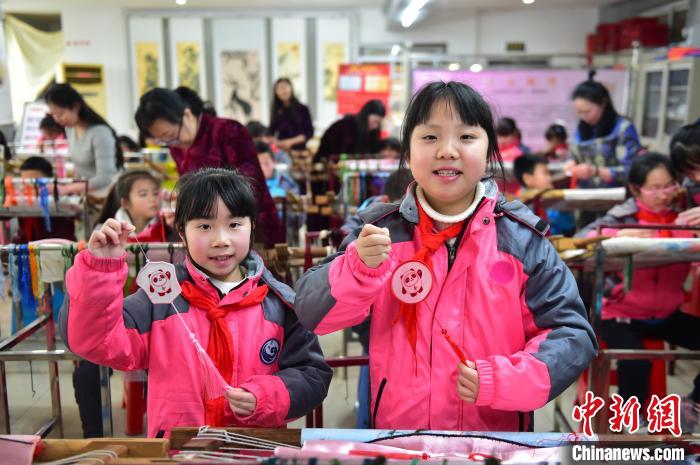 圖為小學生展示繡制好的2022年北京冬奧會吉祥物“冰墩墩”形象。　喻云亮 攝