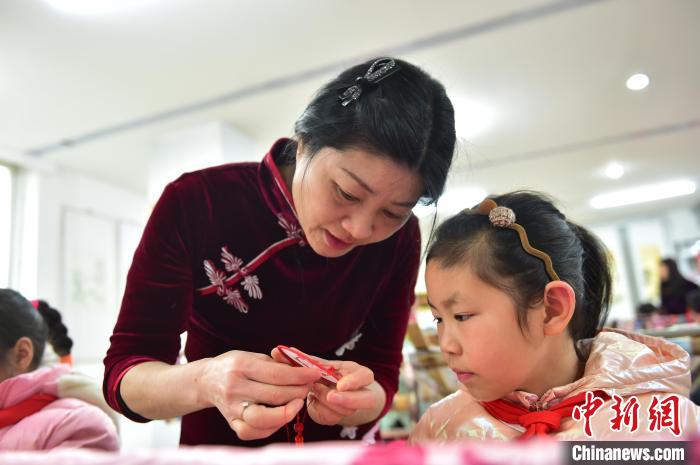 江西省級非遺豫章繡傳承人手把手指導小學生繡制2022年北京冬奧會吉祥物“冰墩墩”形象。　喻云亮 攝