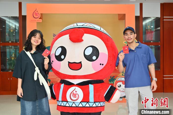 圖為泰國(guó)留學(xué)生手持獻(xiàn)血證與人偶合影。　俞靖 攝