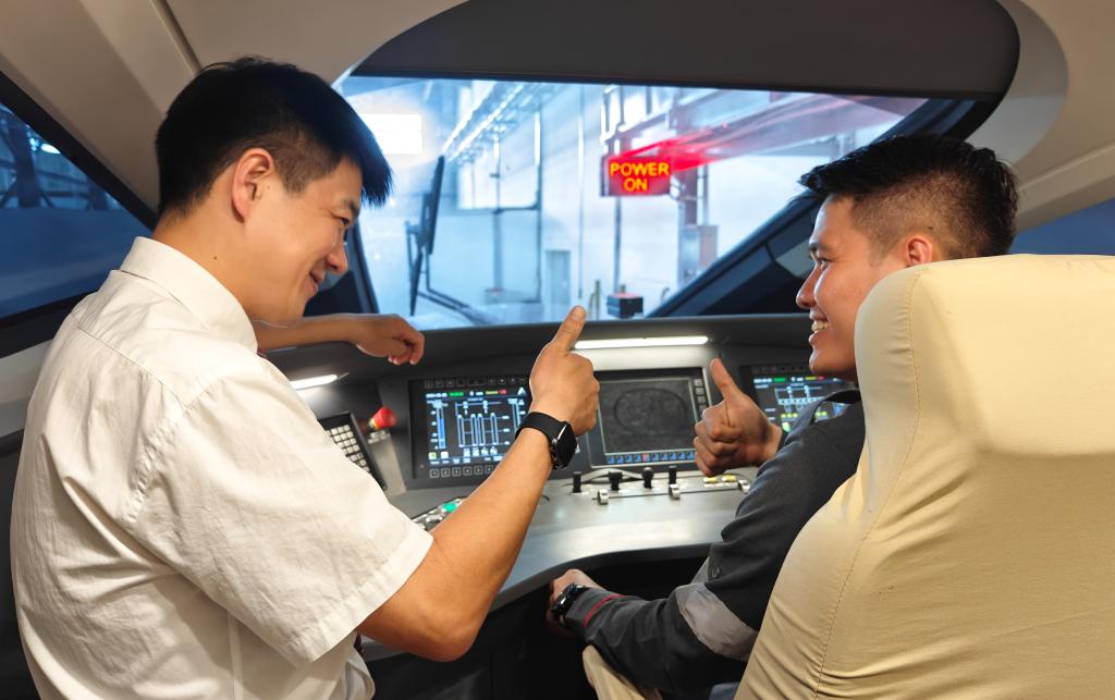 8月25日，在印度尼西亞萬隆的雅萬高鐵德卡魯爾動車所內(nèi)，中國師傅穆振（左）在向印尼火車司機塞蒂亞萬講解動車組出庫前的上電作業(yè)。