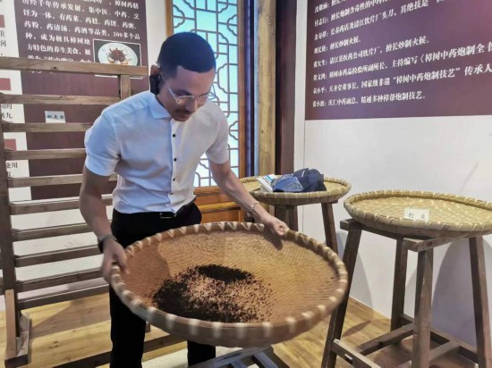 2023“一帶一路”媒體合作論壇聯合采訪團團員在非遺文化展示館體驗中藥炮制技藝。（本報記者 黃超攝）