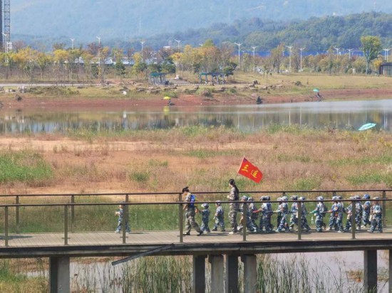 　　10月24日，秋游的幼兒園小朋友在老師帶領下走在清水塘公園里的木橋上。本報記者 常雯宜攝