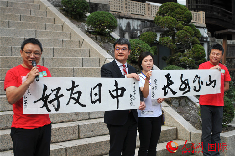 東京中國文化中心主任羅玉泉展示其為本次活動書寫的題詞“中日友好，山高水長”。人民網 蔣曉辰攝