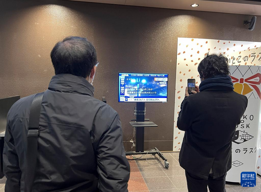 1月2日，在日本東京羽田機場，因機場跑道封閉滯留的乘客觀看兩機碰撞起火事故新聞。新華社記者 岳晨星 攝
