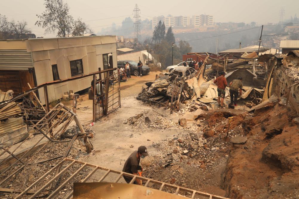 2月3日，在智利瓦爾帕萊索大區比尼亞德爾馬市，當地民眾清理在森林火災中燒毀的房屋。新華社發