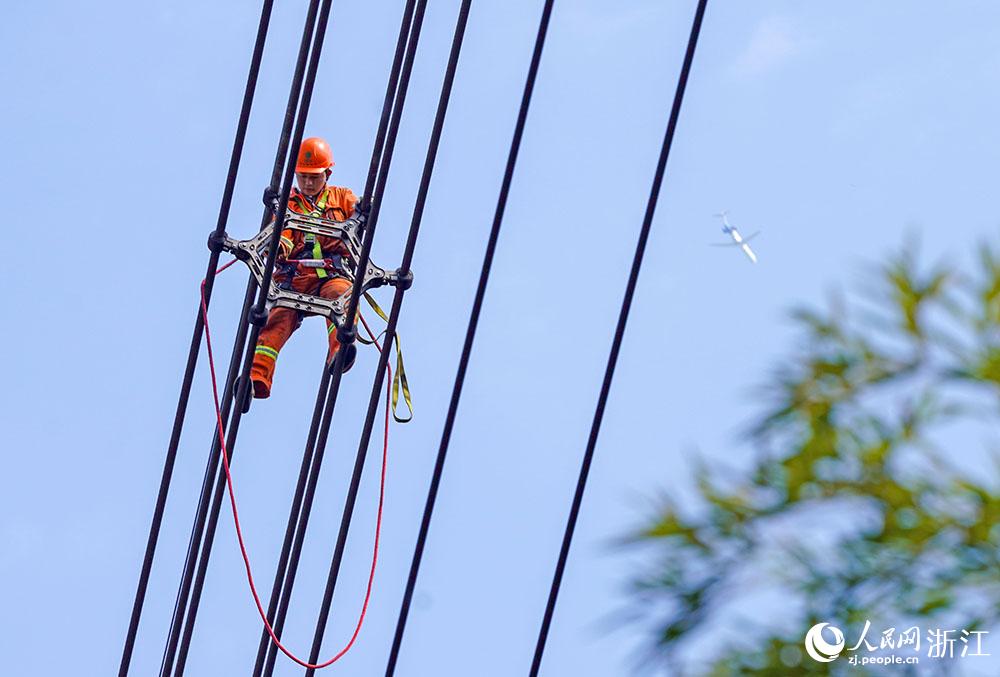 3月11日，在浙江省諸暨市河上鎮，浙江省送變電工程有限公司檢修人員在高空的導線上進行線路檢修維護。人民網 章勇濤攝
