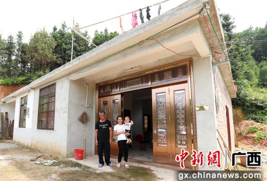 7月4日,在廣西柳州市融安縣大坡鄉崗偉村,脫貧戶肖裕安(左)與妻子、外孫在改造后的房屋前合影。覃慶和 攝