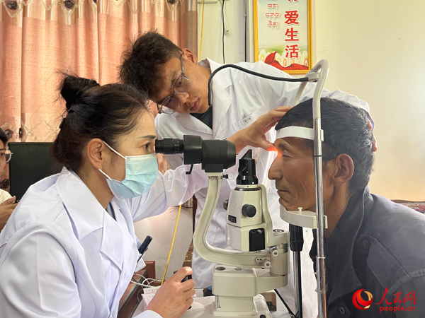 王紅英（左）和團隊成員為達熱村村民檢查眼睛。人民網記者 杜燕飛攝