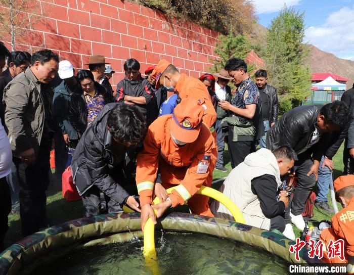 圖為森林消防員為護林員講解滅火裝備的使用方法?！〔际猩窒乐ш?供圖