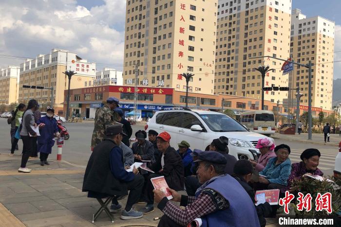 圖為會澤縣城易地扶貧搬遷安置點內，老人們聚在廣場上聊天，身后是他們的新家。　繆超 攝