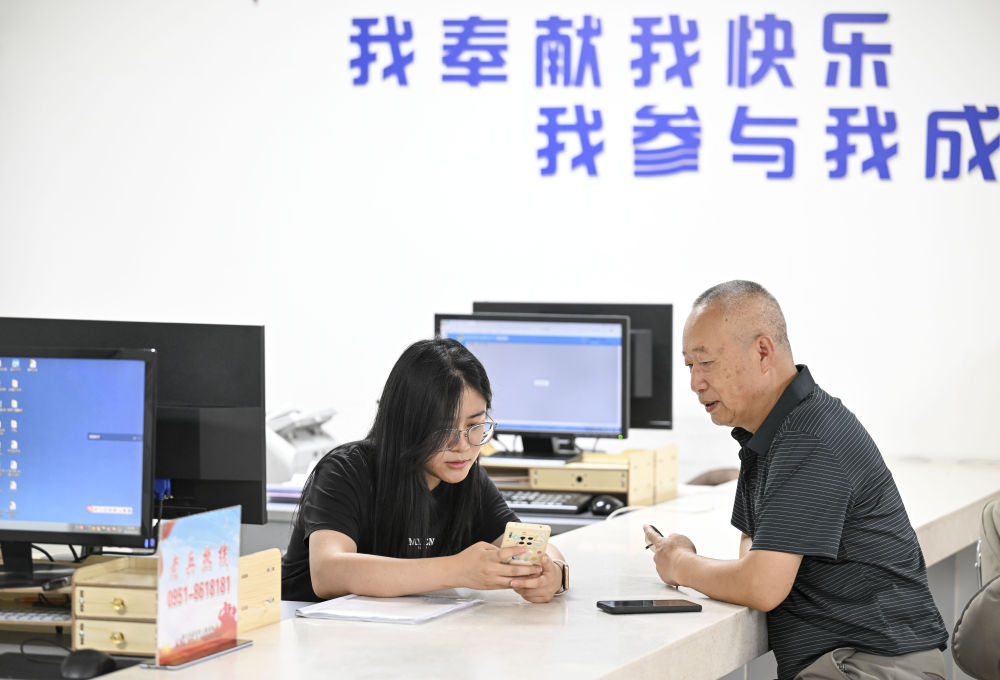 2024年6月20日，在寧夏銀川市金鳳區長城花園社區黨群服務中心，工作人員幫助居民辦理業務。圖片來源 新華社