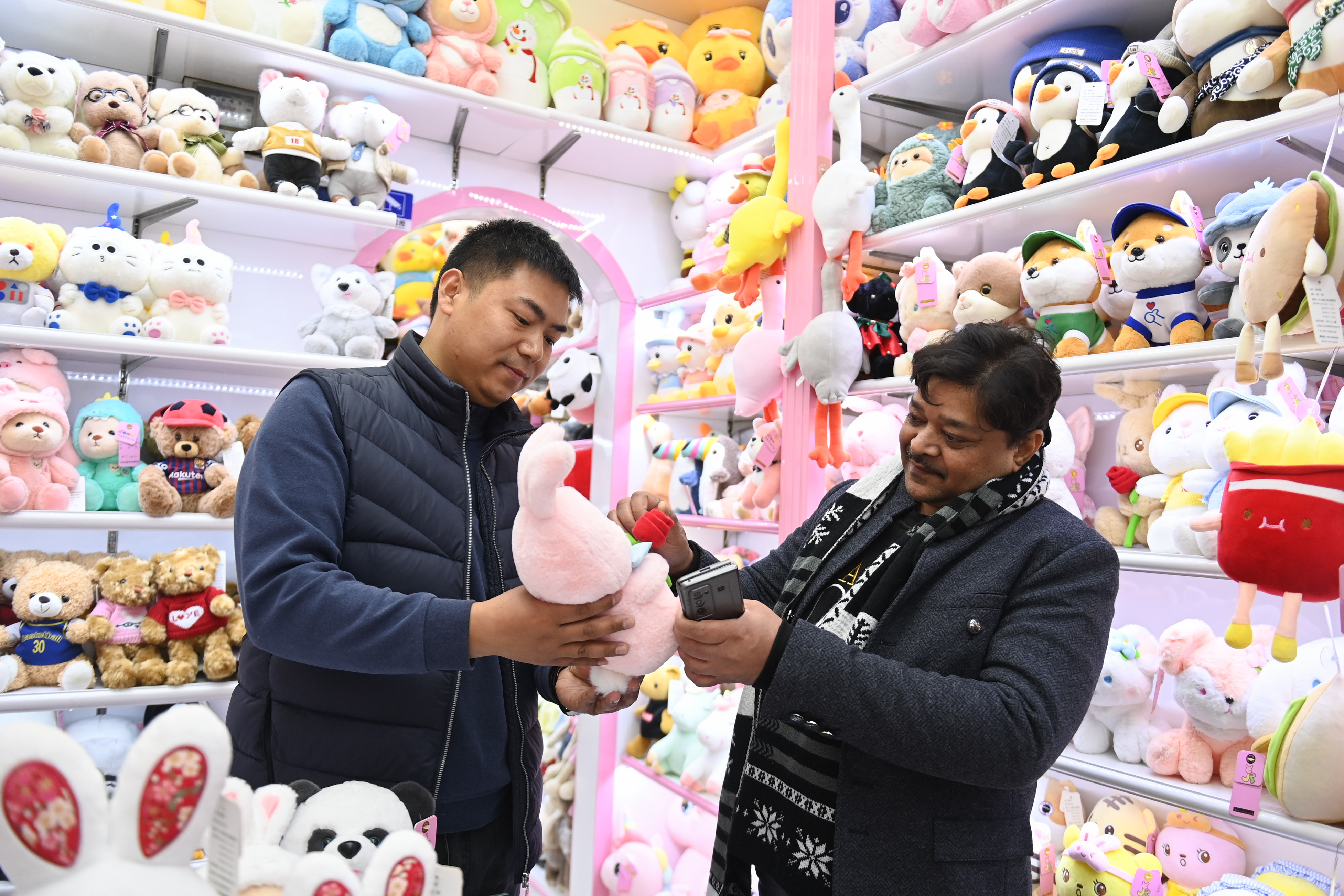 2023年2月2日，來自印度的客商（右）在義烏國際商貿城的一家玩具店鋪內選購。