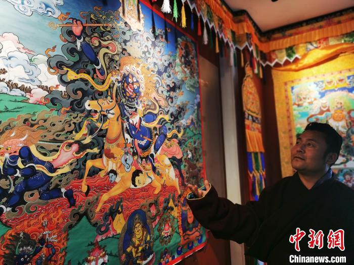 圖為久美尖措展示唐卡作品?！?zhí)砀?攝