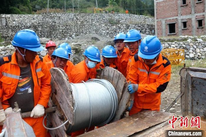 國網四川送變電公司搶險隊員將重達370公斤的鋼絞線搬上車。　劉湘釩 攝