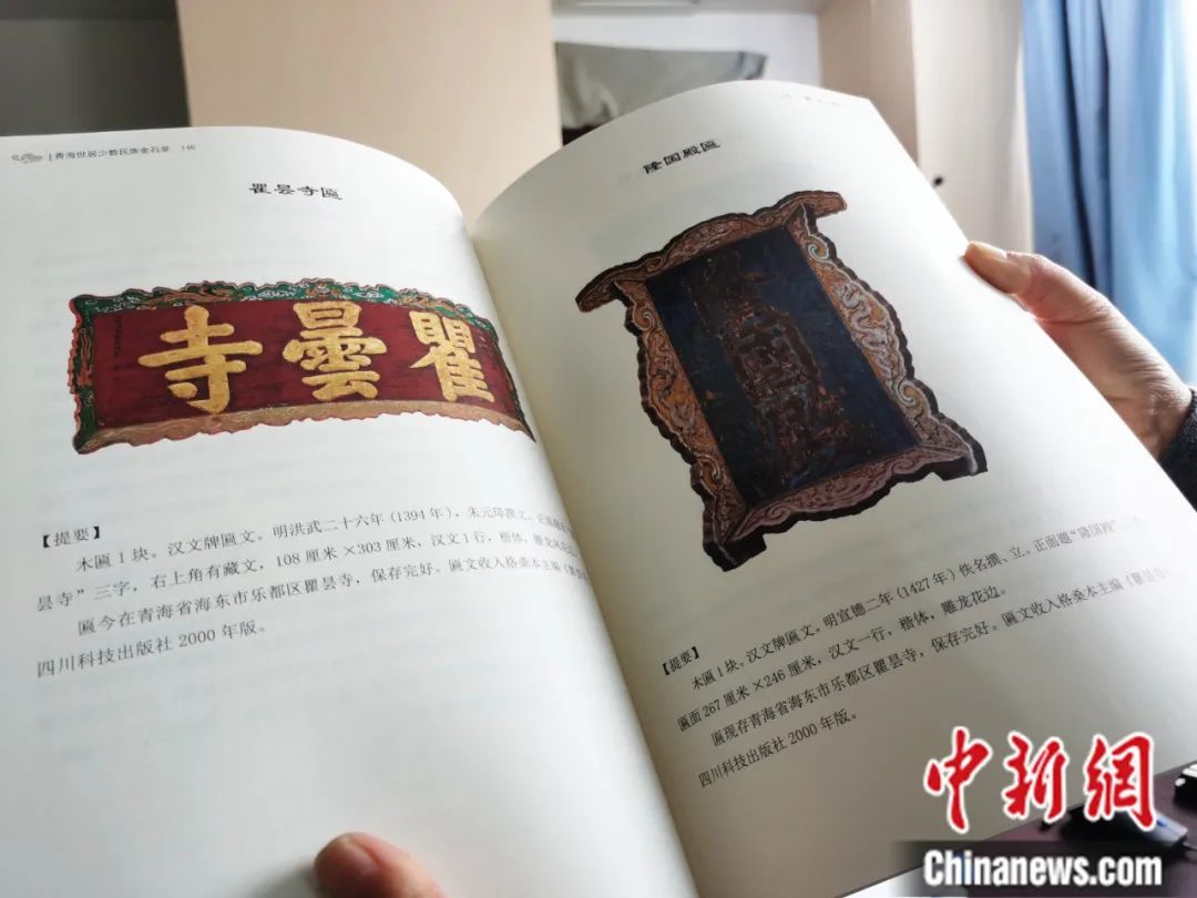 古籍保護(hù)人員展示介紹明代朱元璋撰寫(xiě)的青海瞿曇寺匾(左)的出版書(shū)籍。張?zhí)砀?攝