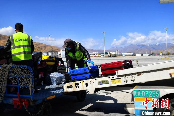 圖為機(jī)場(chǎng)工作人員傳送旅客行李箱。　周航 攝