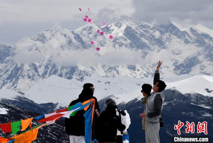 圖為5月14日，游客在西藏林芝色季拉山觀景臺拋灑“隆達”(風馬旗，藏族民眾的一種祈福方式)。　李林 攝