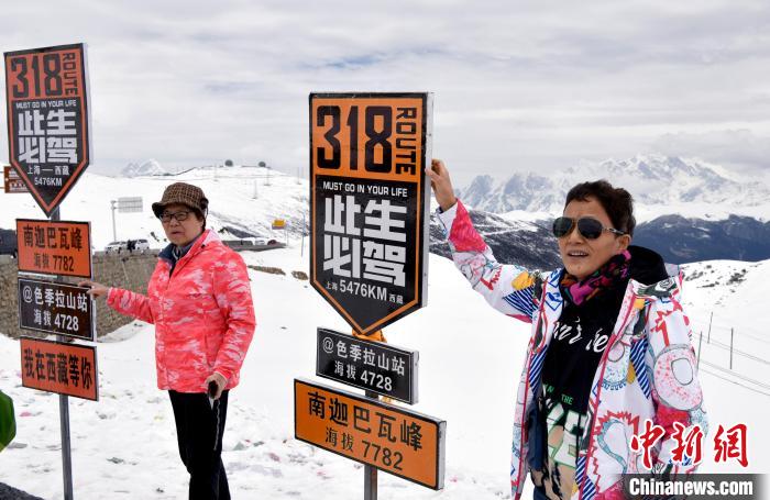 圖為5月14日，西藏林芝色季拉山觀景臺，游客與南迦巴瓦峰合影。　李林 攝